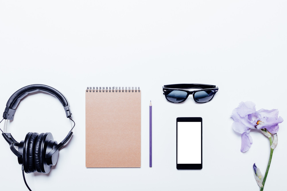 Blue flower, headphones, notebook and mobile phone on a white background, top view