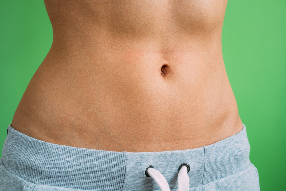 Close up of Belly slim girl in sweat pants on a green background, not isolated.