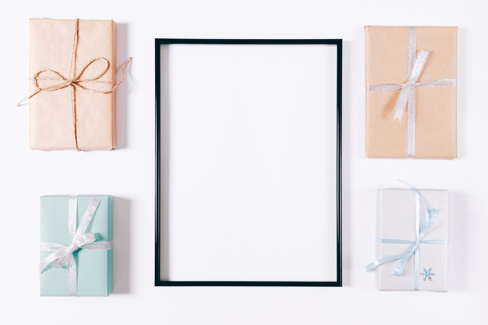 Top view of a box with gifts and blank frame on a white background