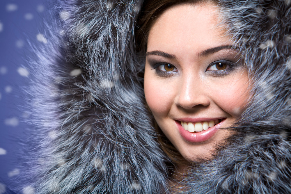 Portrait of beautiful female wearing fur cap and smiling