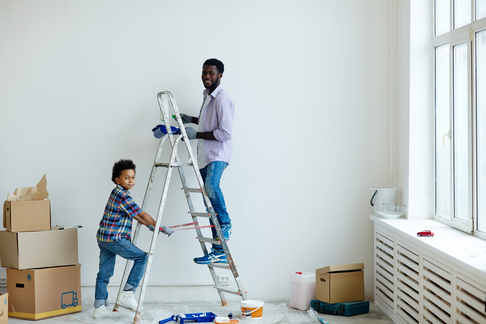 Father and his little son painting walls of new flat