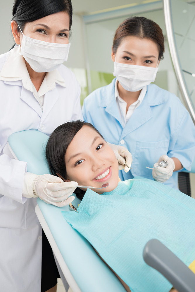 Vertical portrait of a teenager and dental doctors during the dental procedure