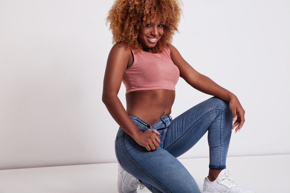 black woman with big afro hair wears jeans and top
