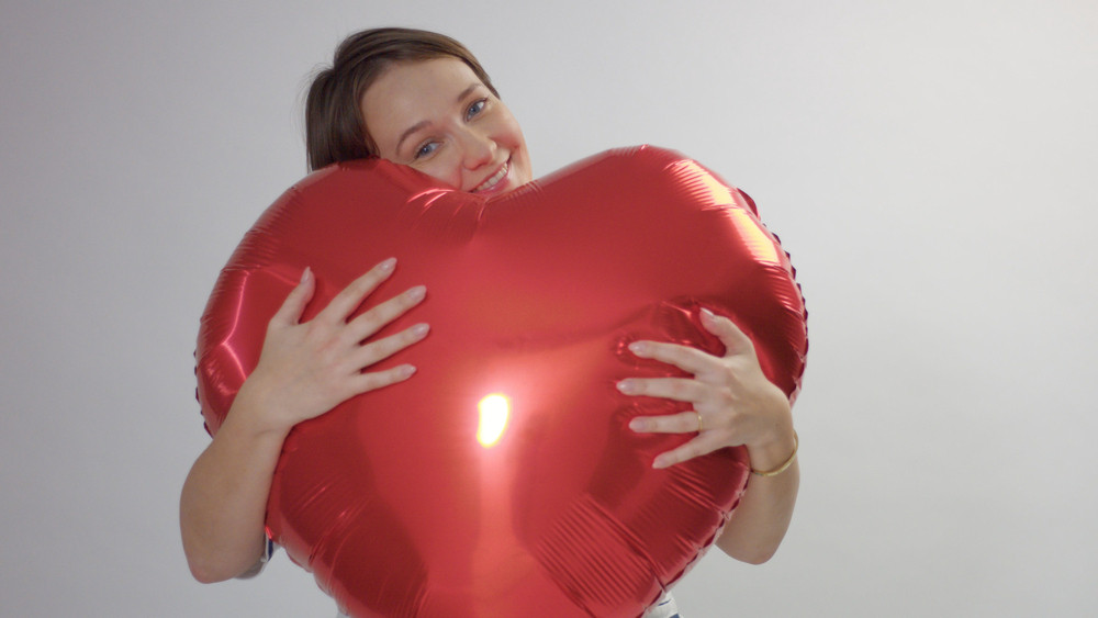 caucasian woman hugs a huge red heart and hold it joying