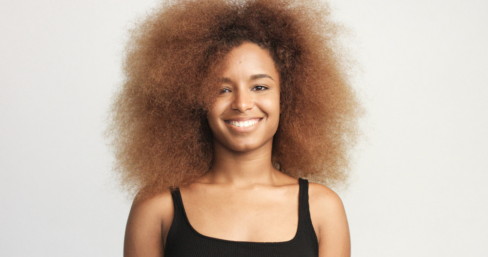 Mixed Race Black Woman With Blonde Curly Hair In Studio Happy