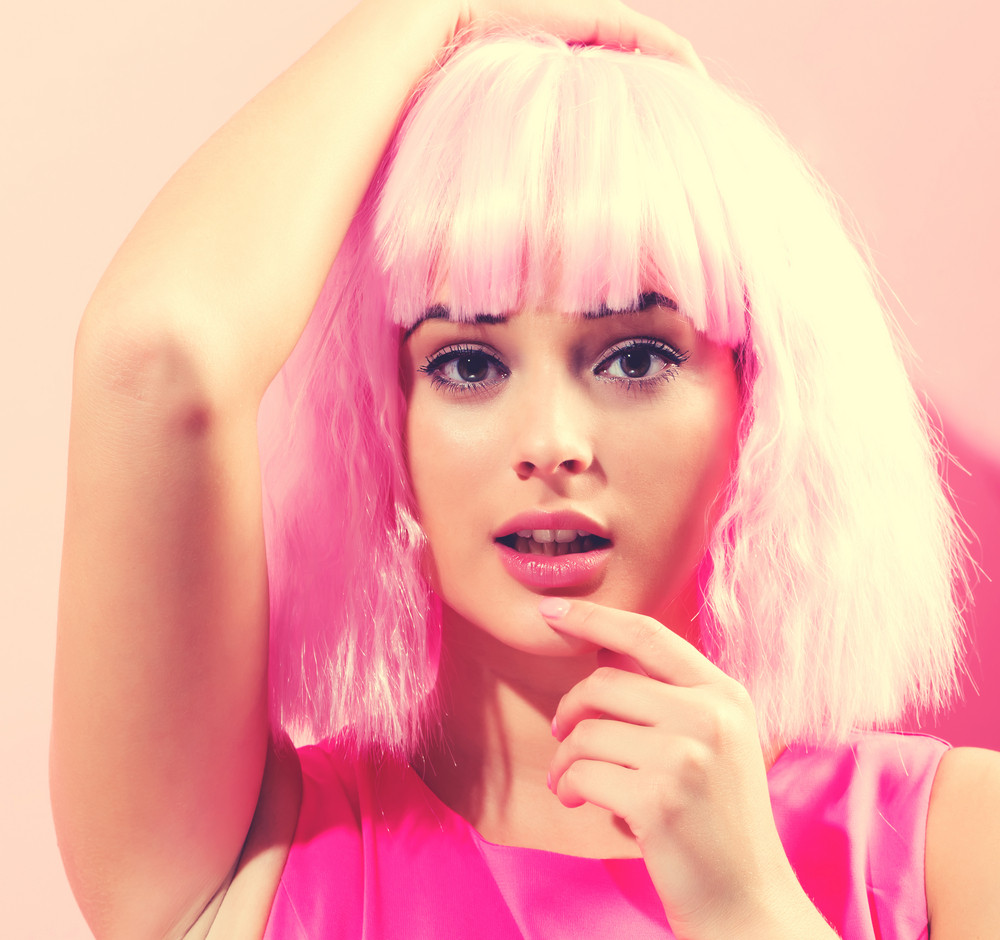 Beautiful woman in a bright pink wig on a pink background