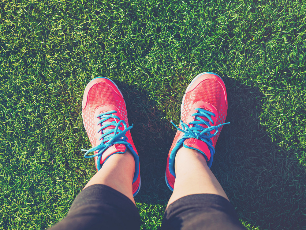 Female runner looking down at her feet in a grass field