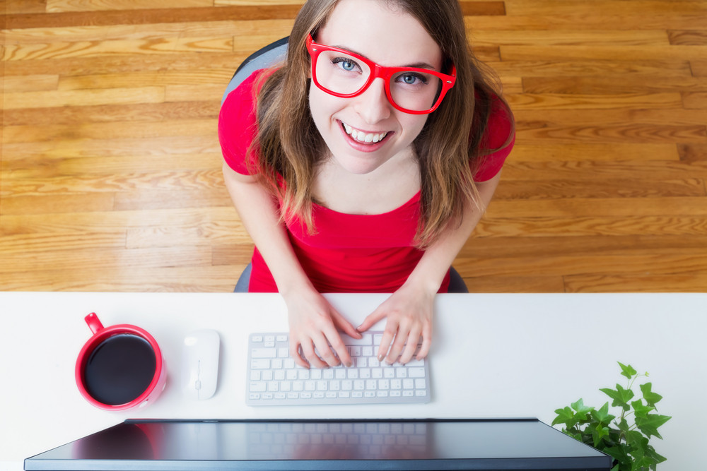 Happy young woman smiling while working in her home office from a high angle