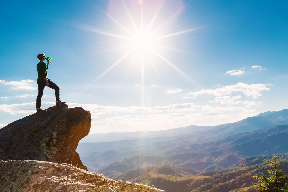 Man walking on the edge of a cliff high above the mountains Royalty ...