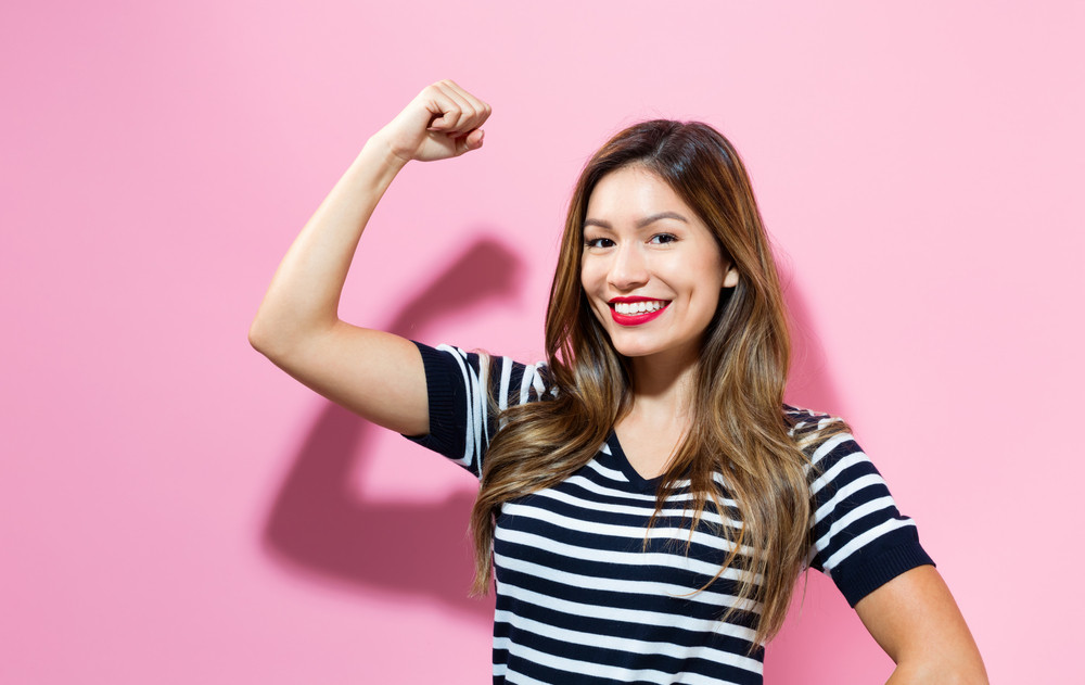 Powerful young woman on a pink background