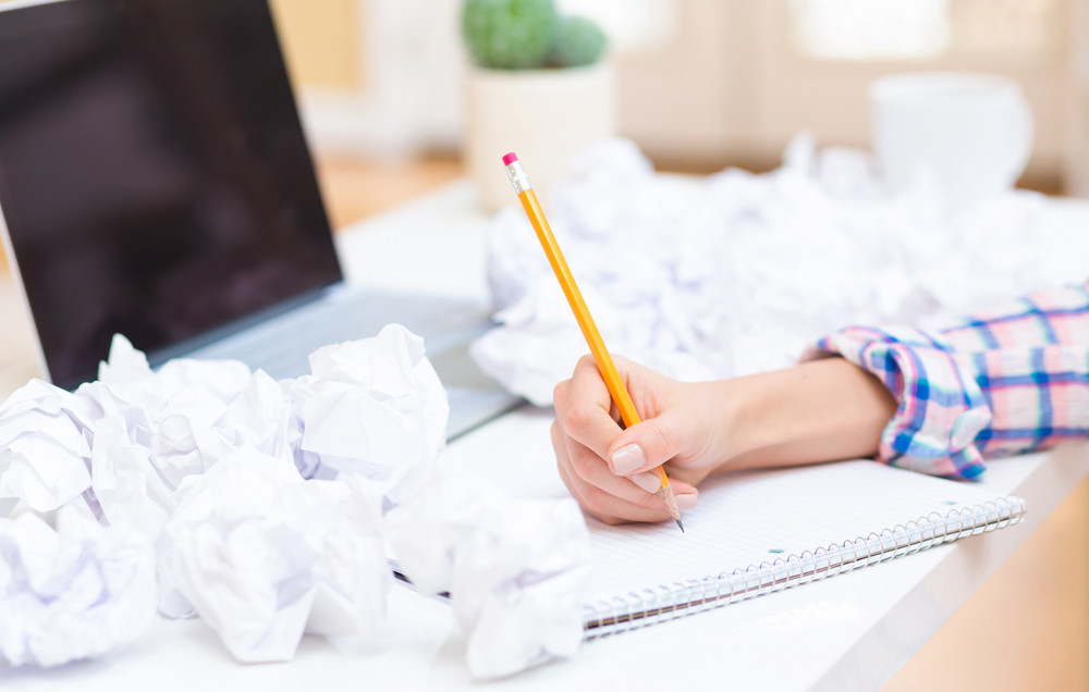 Woman writing on a notebook with crumpled paper balls in an office