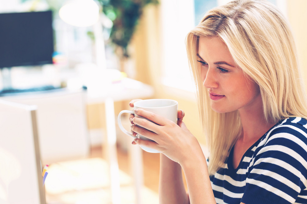 Young woman drinking coffee in a bright office space