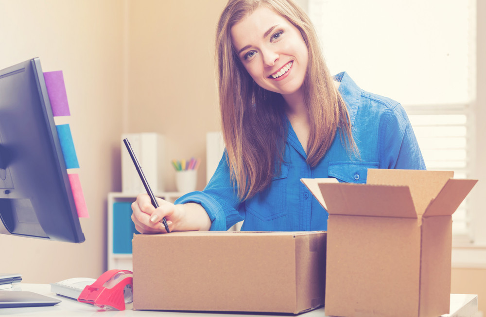 Young woman packing boxes to be shipped in her home office