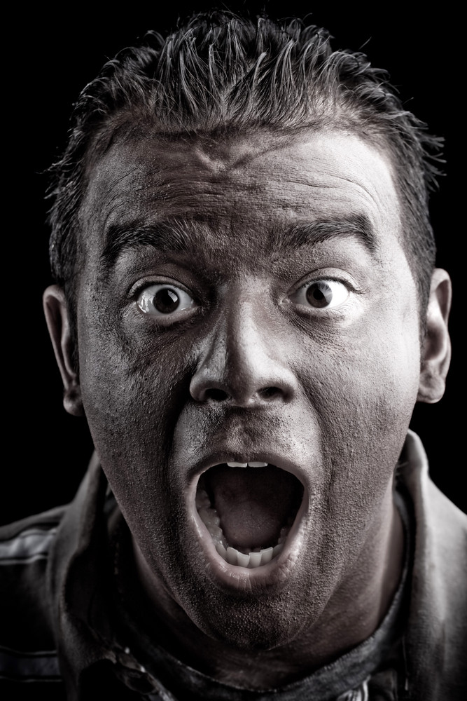 A frightened man with dark skin has a shocked or surprised look on his face.