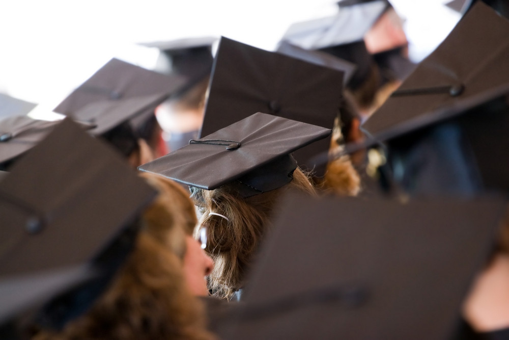 A group of college or high school graduates wearing the traditional cap and gown. Shallow depth of field.