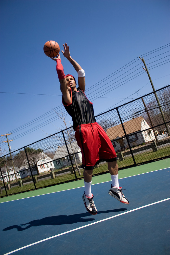 A young basketball player shooting a three point jump shot.