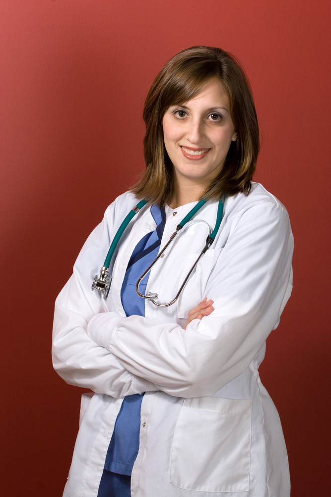 A young woman doctor with her arms crossed isolated over a red background