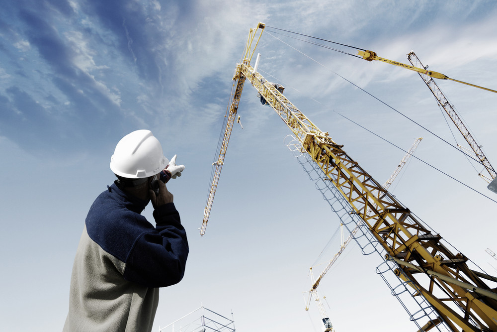 building worker pointing at construction crane