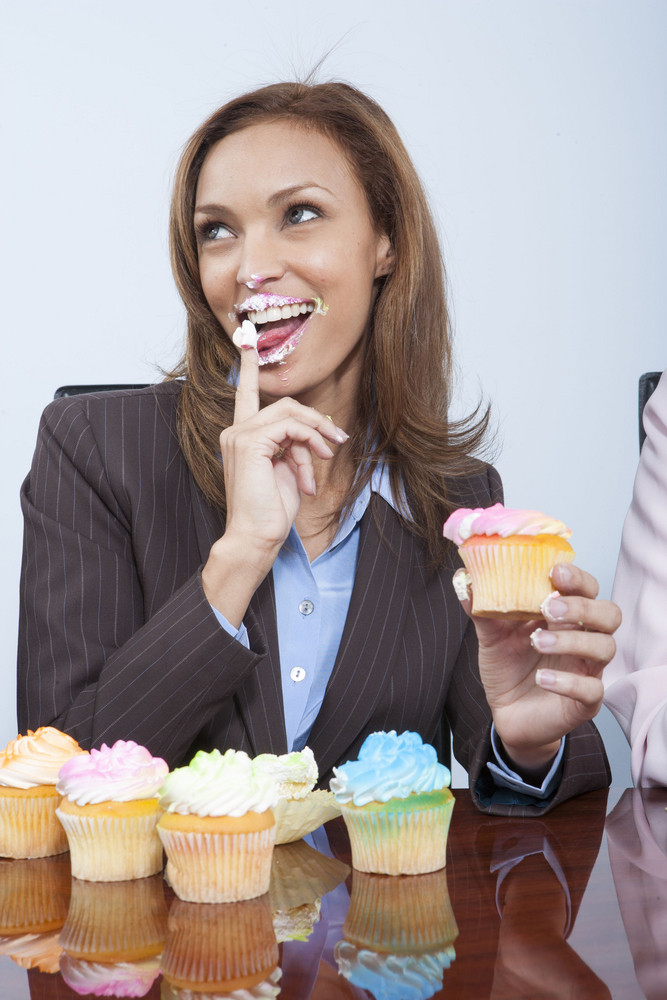 Business colleagues eating cupcakes in office