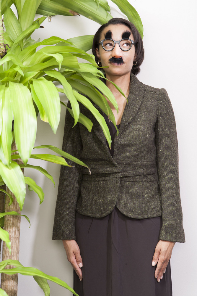 Business person hiding behind plant in office