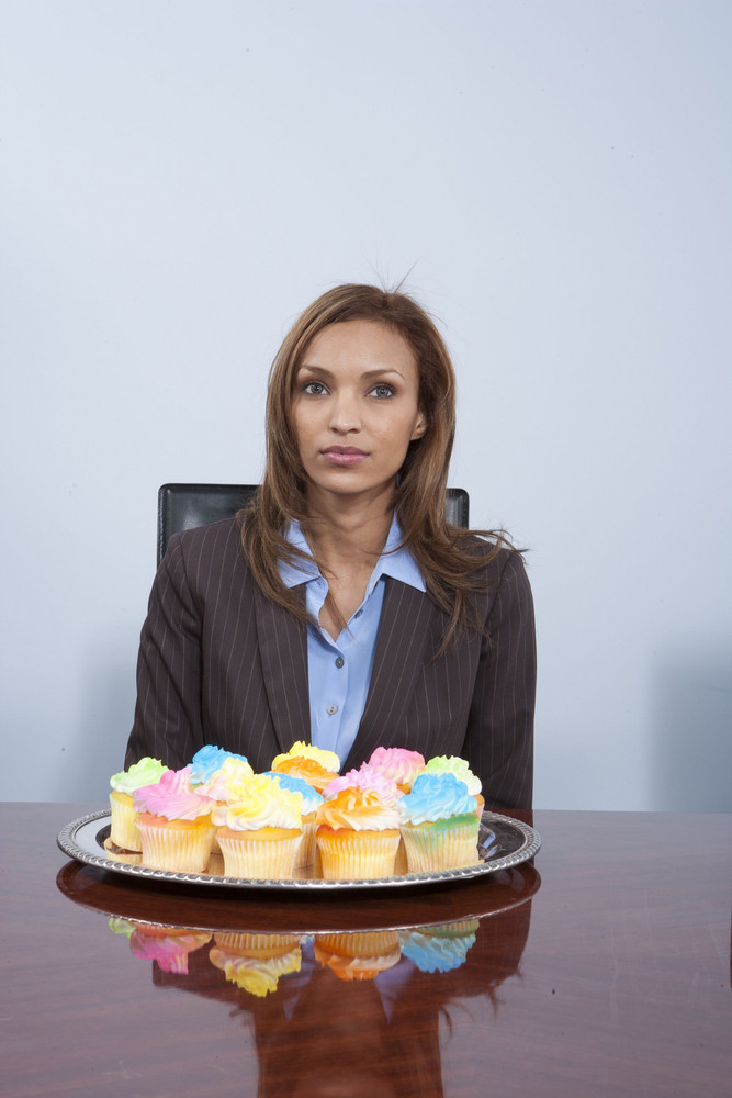 Businesspeople eating cupcakes in office
