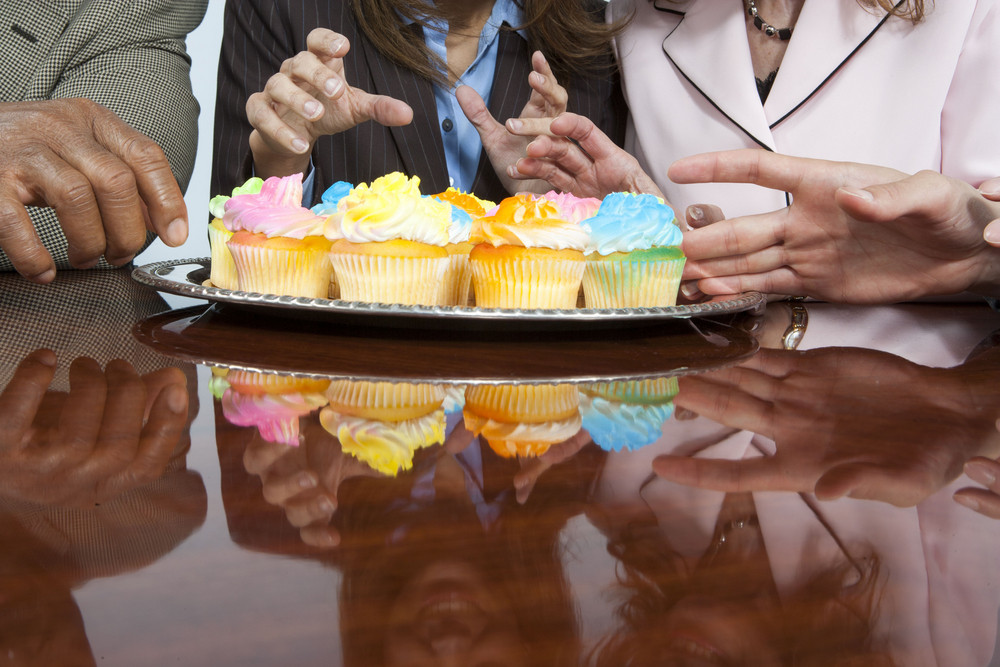 Businesspeople eating cupcakes in office
