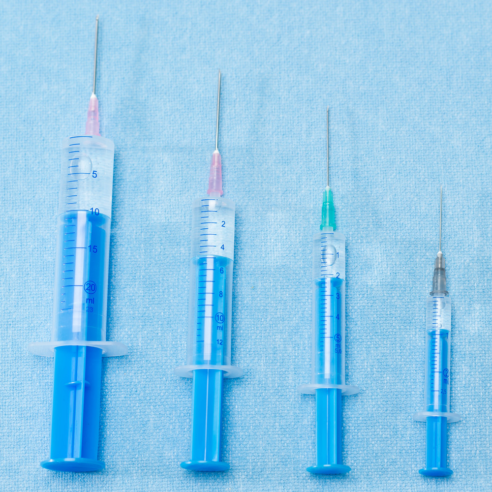 Hypodermic needles injections on blue medical cloth placed in line ...