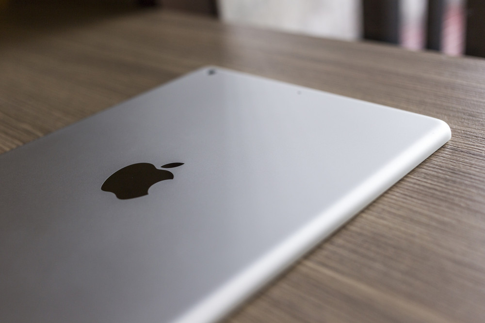 CHIANG MAI, THAILAND - OCTOBER 21, 2014: Logo of Apple in back Apple iPad air on wood desk.
