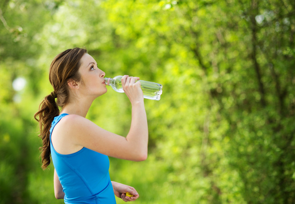 Athlete refreshing with a bottle of water during the outdoor exercise