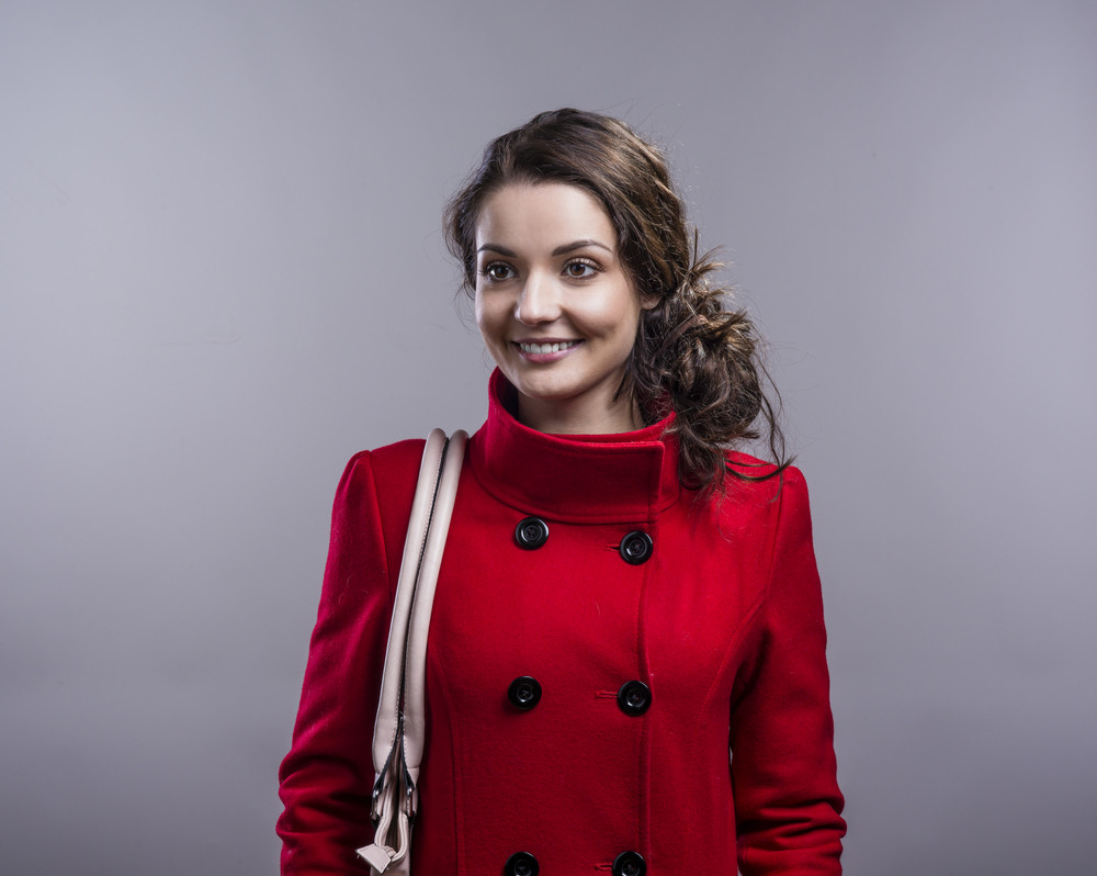 Beautiful woman in red coat. Studio shot on gray background ...