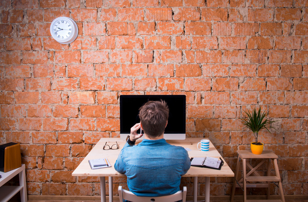 Business Person Sitting At Office Desk Talking On Phone Against