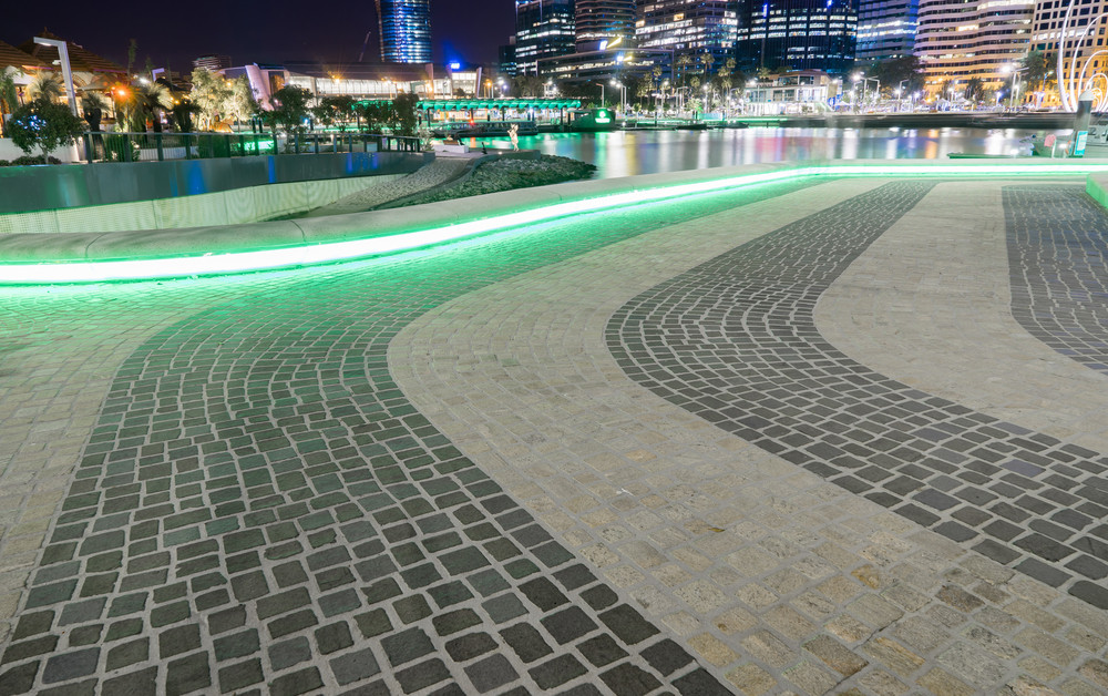 Green neon lights circulating underneath the stone seating reflecting on the stone pavement in Perth tourism hot spot Elizabeth Quay