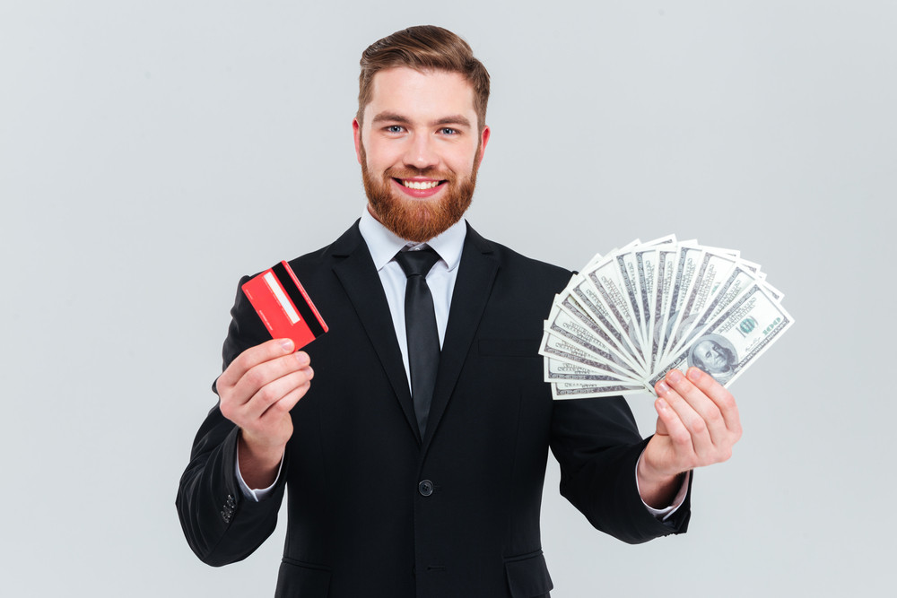 Happy bearded business man in black suit holding credit card and money ...