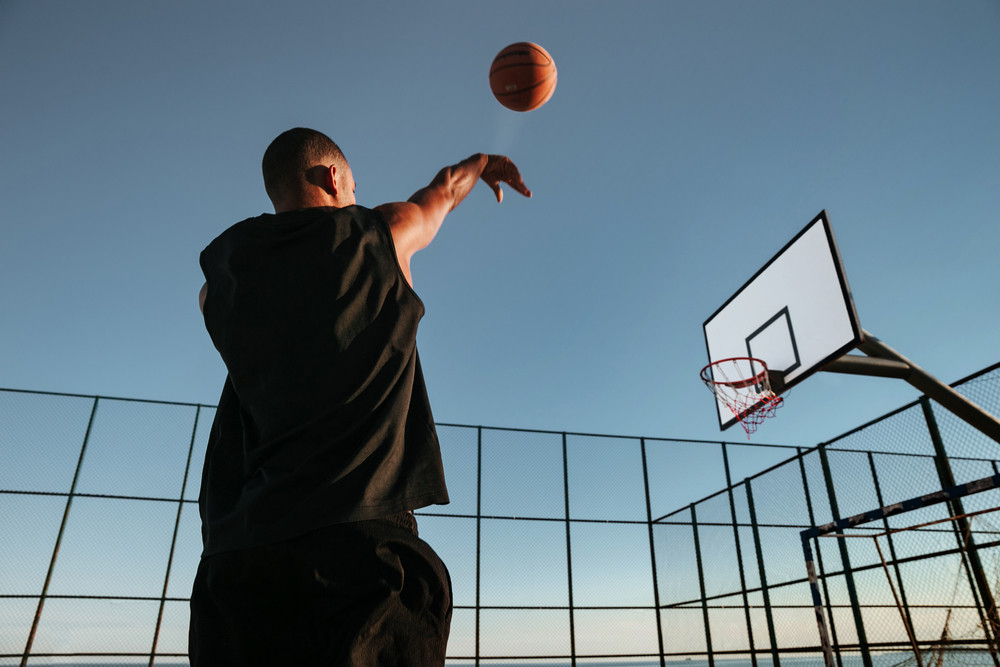 Portrait of a basketball player taking a jump shot on an outdoor basketball court