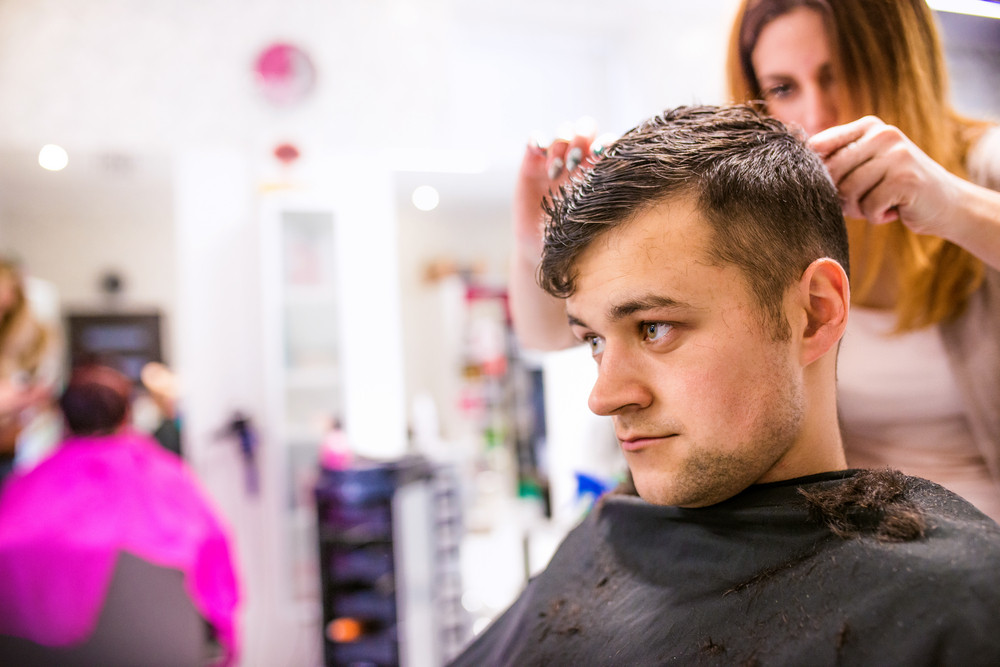 Professional Hairdresser Cutting Hair Of Her Young Client Making