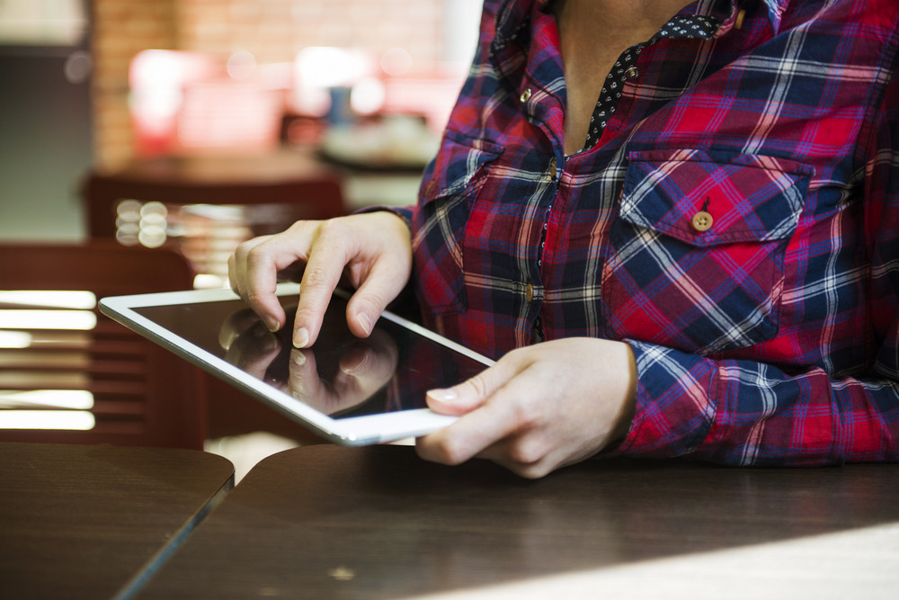 Smiling girl spending time in a cafe using digital tablet
