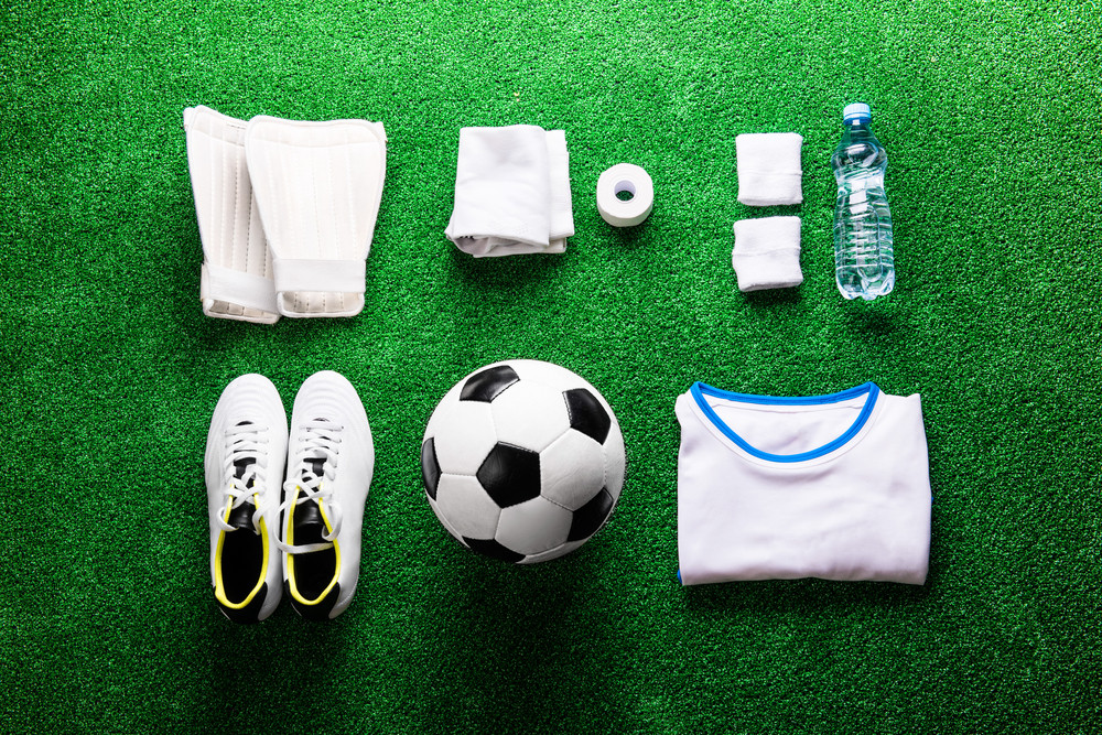 Soccer ball,cleats and various football stuff against artificial turf ...