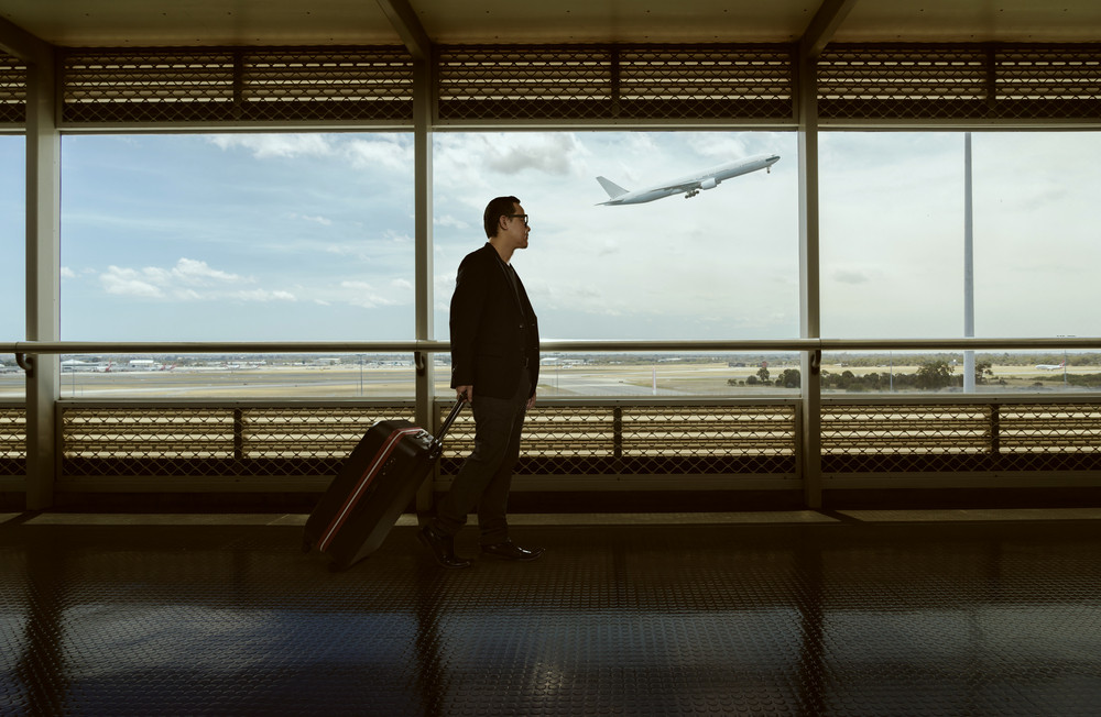 traveling \
man and luggage walking in airport terminal and air plane flying outside