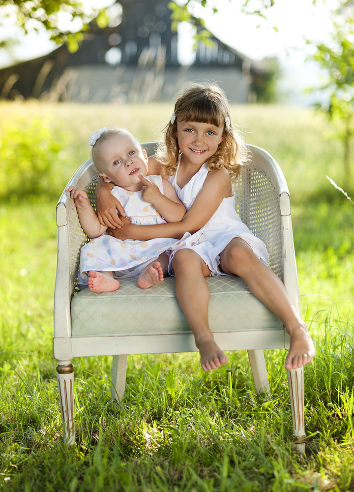 Two cute little sisters laughing and playing in green ...