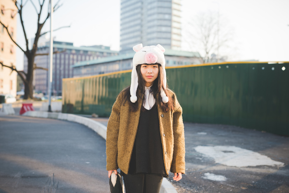 young beautiful asian hipster woman in the city - wearing funny piggy winter cap