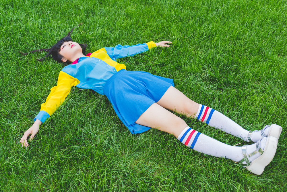 young beautiful asian millennial woman nonconformist laying on the grass relaxing - sleeping, death, relaxing concept