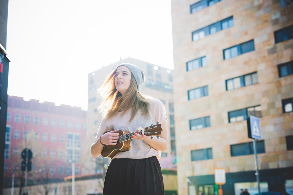 young beautiful blonde hipster woman in the city with ukulele