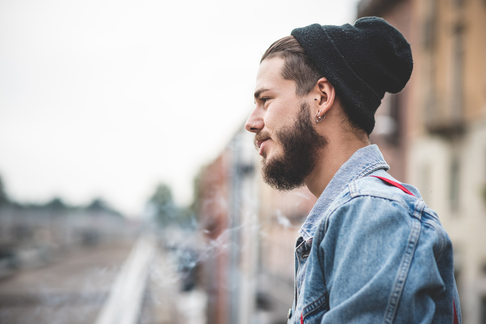 young handsome bearded hipster man smoking cigarette in the city ...