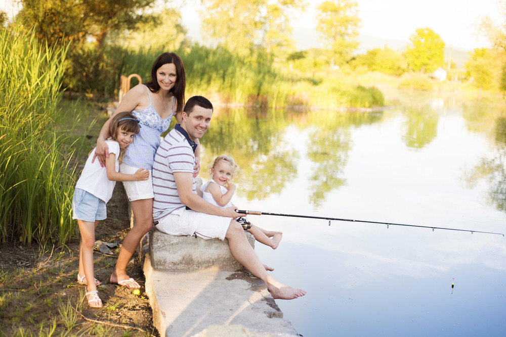 Young happy family with kids fishing in pond in summer Royalty-Free ...