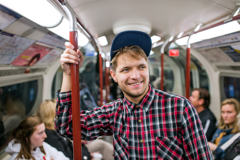 Young hipster man in checked shirt standing in a crowded subway train