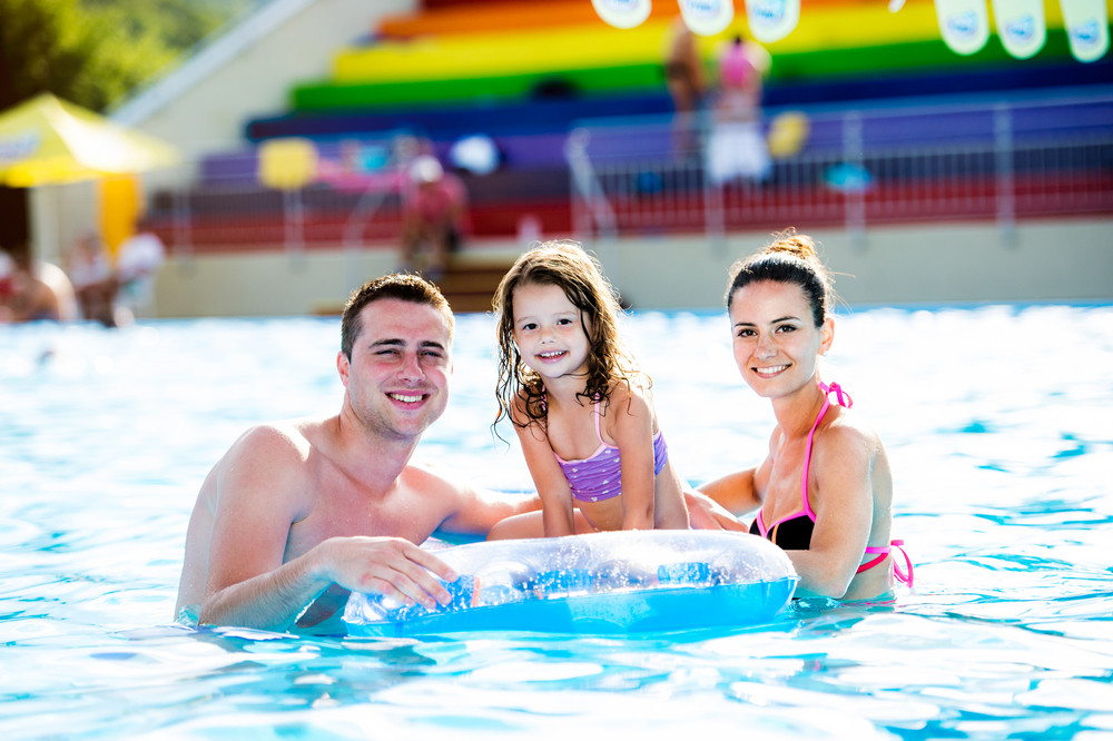 Young mother and father with their daughter sitting on pool lilo in ...