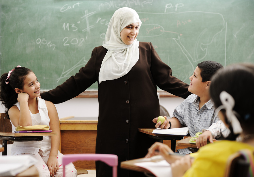 Muslim female teacher with children in classroom in modern school