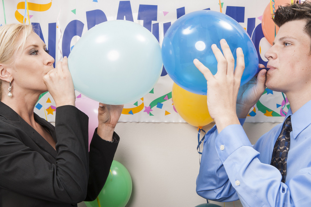Office staff blowing up balloons