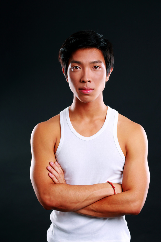 Portrait of a serious asian man with arms folded on black background