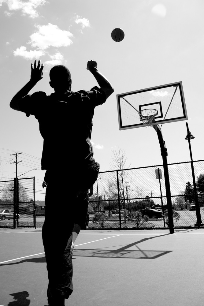 Silhouette of a basketball player shooting the ball at the basket ...